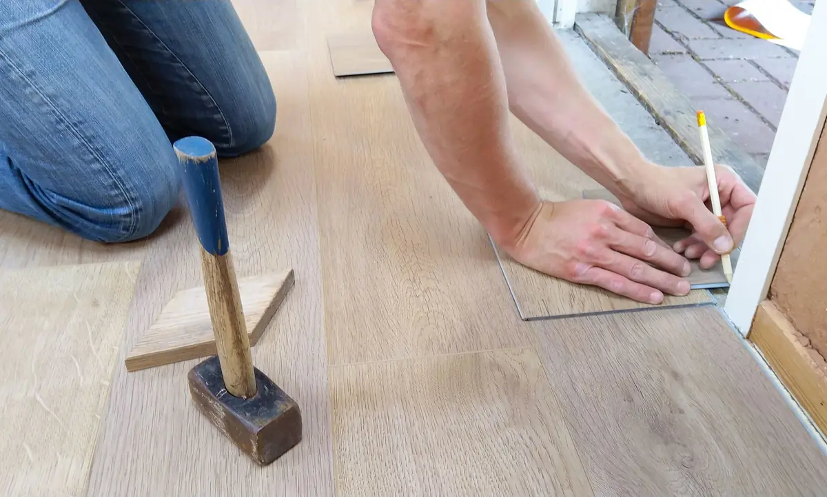 Vakman tekent een plank nauwkeurig af bij het leggen van een lichte vloer