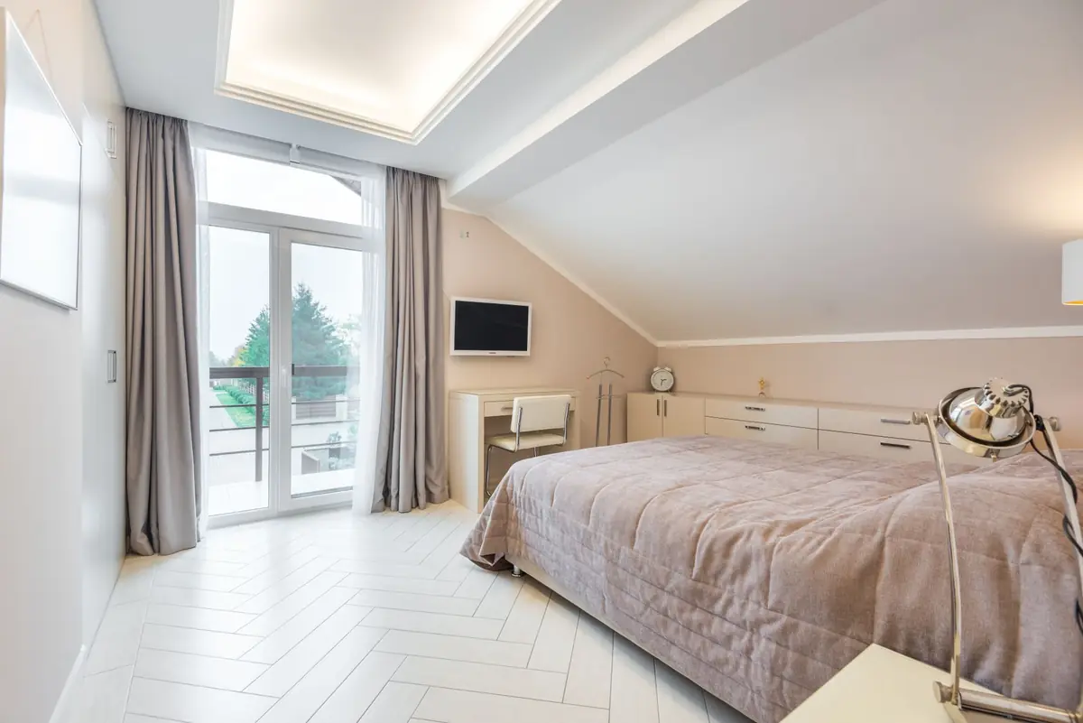 Lichte slaapkamer met bed, balkonramen en een rustige lichte vloer